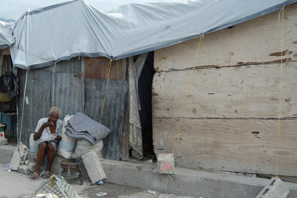 Haitian woman, eating outside her makeshift home following the earthquake in 2010. Photo by Lesa Brackbill.